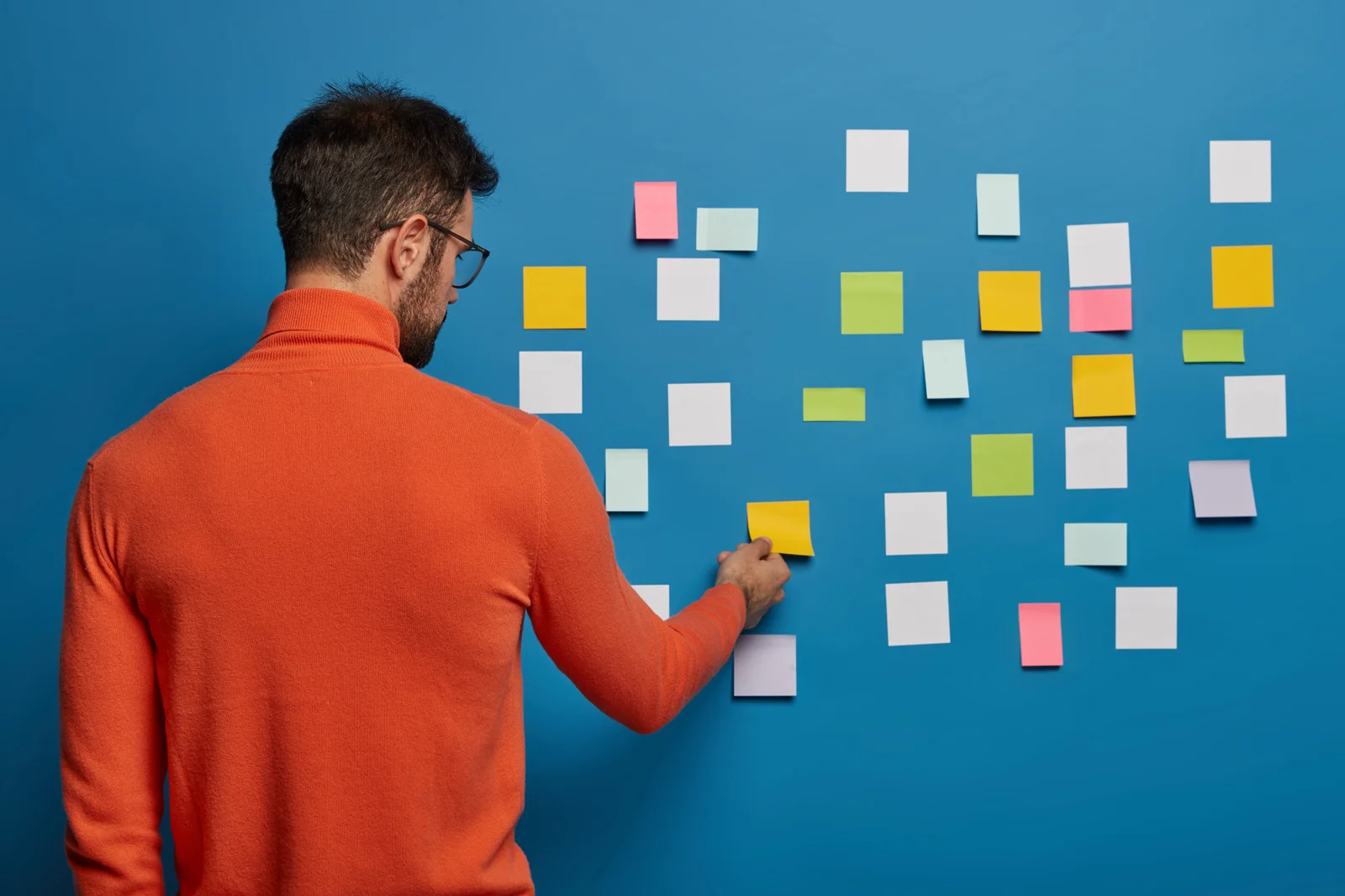 Personne organisant des notes colorées sur un mur pour illustrer la priorisation des actions de remédiation Active Directory