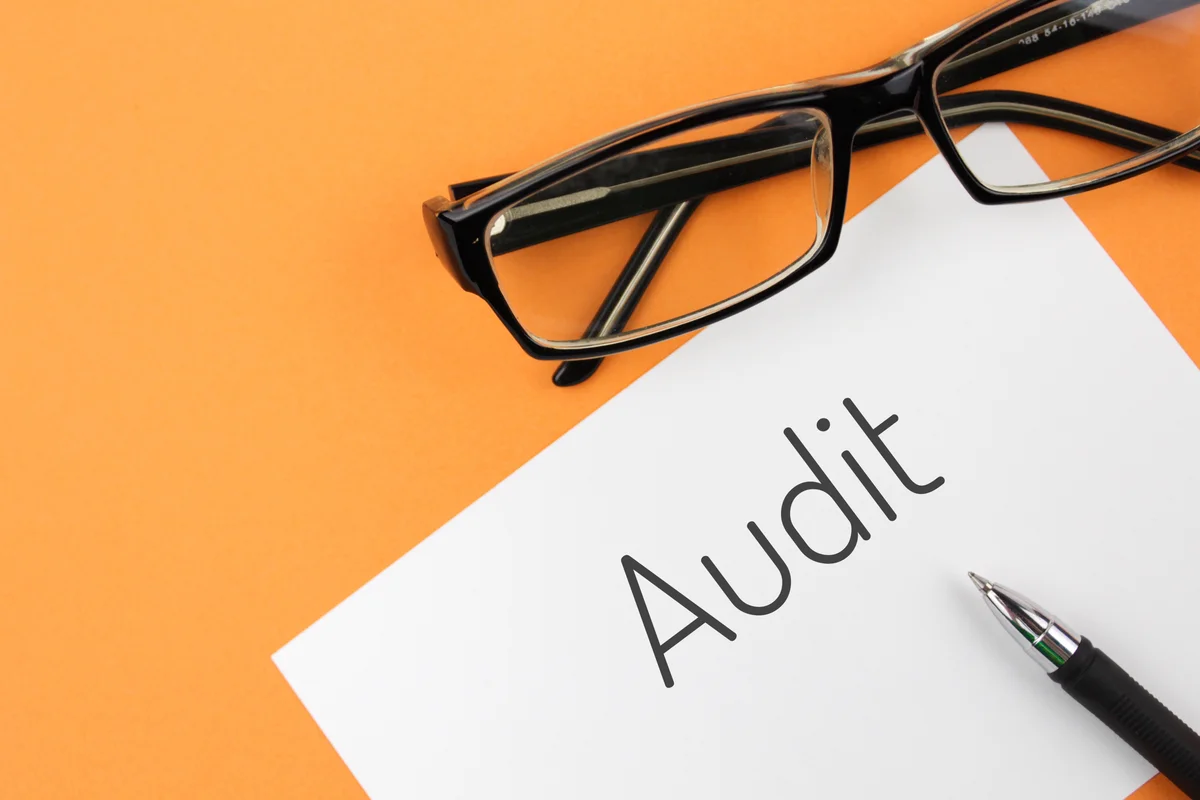 Document Audit avec lunettes et stylo sur fond orange, illustrant l'audit Active Directory