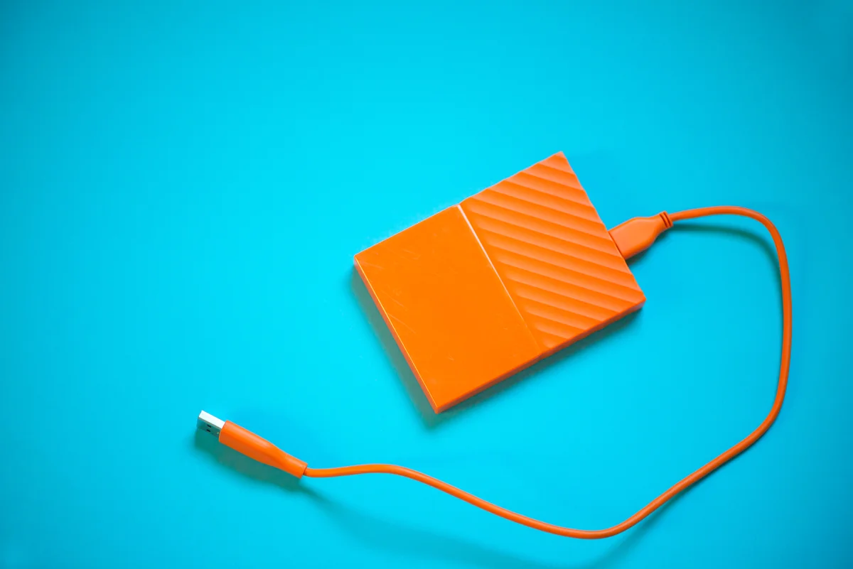 Disque dur externe orange avec câble USB, illustrant la sauvegarde Active Directory